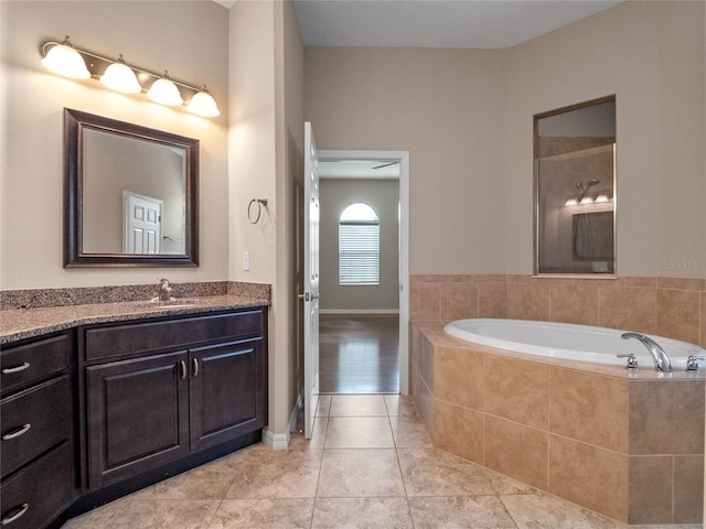 bathroom with vanity, a relaxing tiled tub, and tile patterned floors