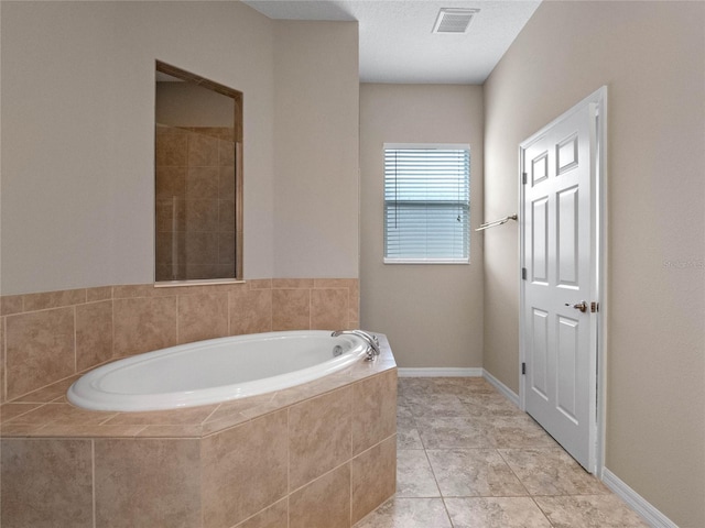 bathroom with tile patterned floors, a textured ceiling, and tiled tub