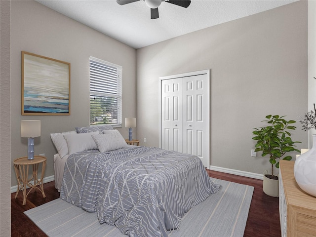 bedroom with a closet, a textured ceiling, dark wood-type flooring, and ceiling fan