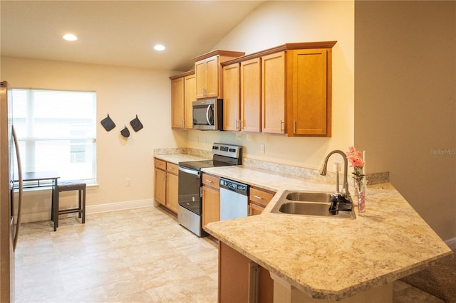 kitchen featuring lofted ceiling, sink, light stone countertops, appliances with stainless steel finishes, and kitchen peninsula