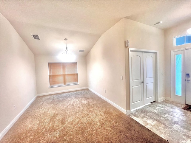 carpeted foyer entrance with vaulted ceiling and a textured ceiling