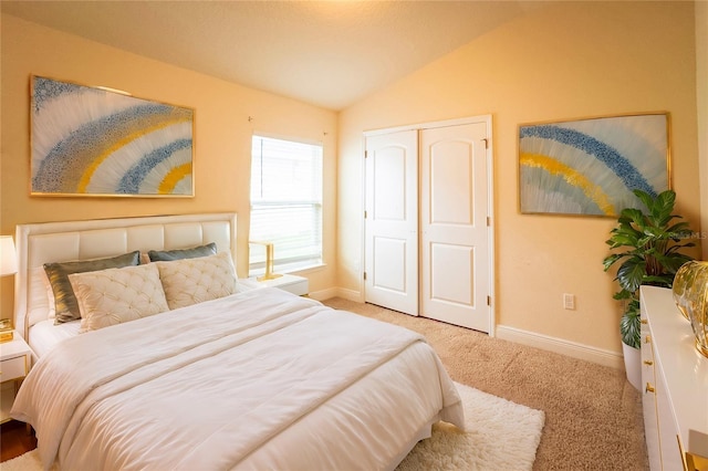 bedroom with a closet, light colored carpet, and vaulted ceiling