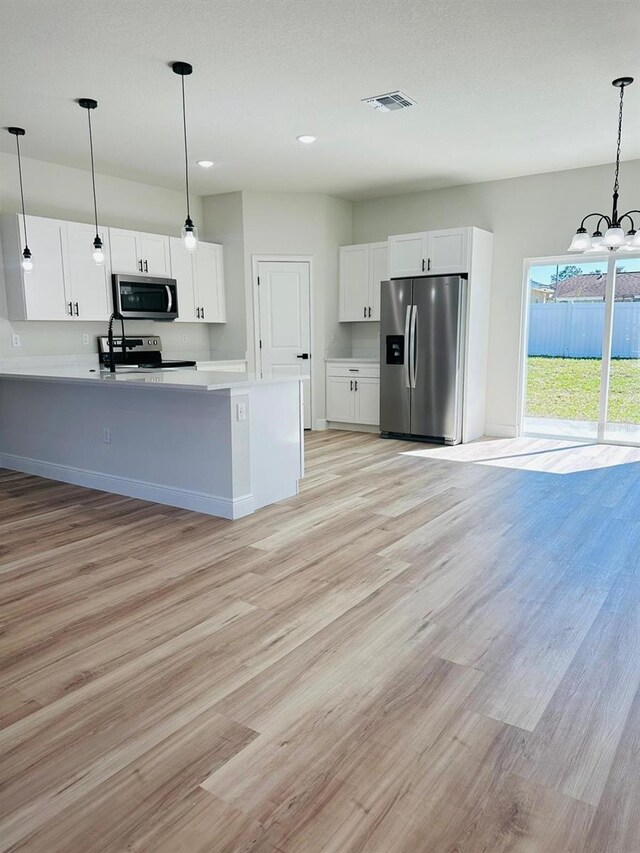 kitchen featuring stainless steel appliances, light wood-type flooring, white cabinets, a chandelier, and light countertops
