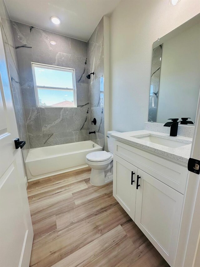 full bathroom with tub / shower combination, toilet, vanity, wood finished floors, and recessed lighting