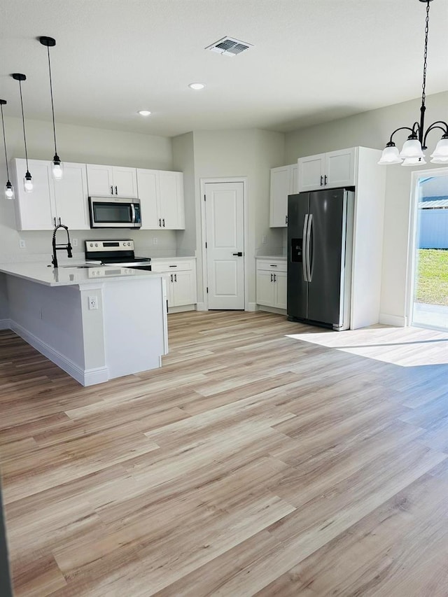 kitchen with light hardwood / wood-style flooring, white cabinets, decorative light fixtures, and stainless steel appliances