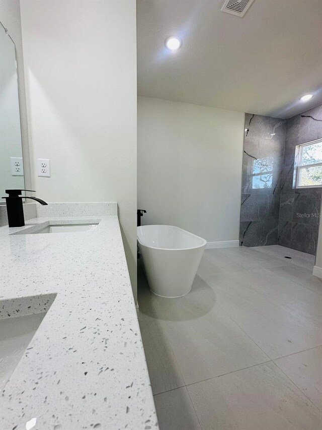 bathroom featuring a walk in shower, a freestanding bath, vanity, recessed lighting, and tile patterned floors