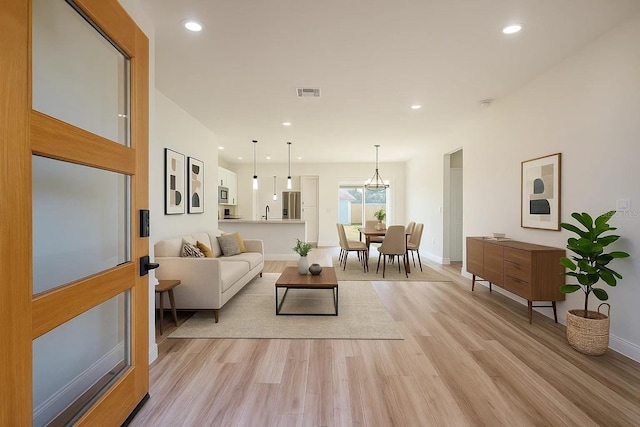 living room with light wood-type flooring, baseboards, and recessed lighting
