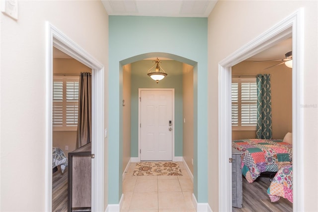 interior space with light tile patterned floors, baseboards, and arched walkways