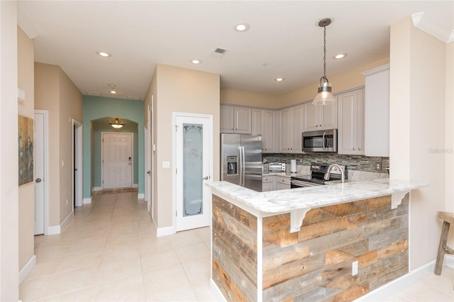 kitchen featuring light stone counters, visible vents, backsplash, appliances with stainless steel finishes, and a peninsula