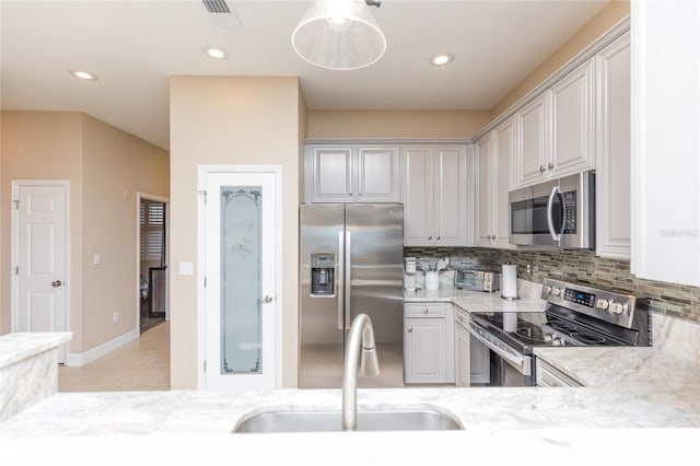 kitchen with light tile patterned floors, decorative backsplash, stainless steel appliances, a sink, and recessed lighting