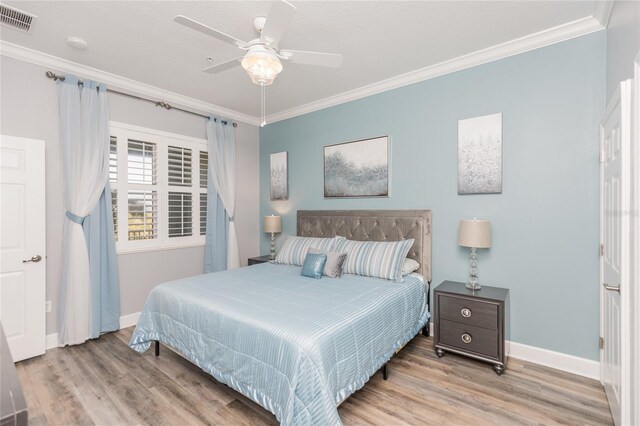 bedroom with ornamental molding, visible vents, and wood finished floors