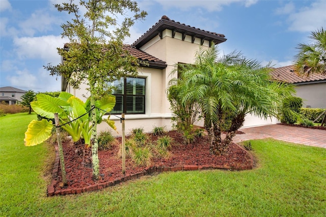 3951 Carrick Bend Dr, Kissimmee, FL 34746 - view of property exterior featuring a garage, a yard, decorative driveway, a tiled roof, and stucco siding
