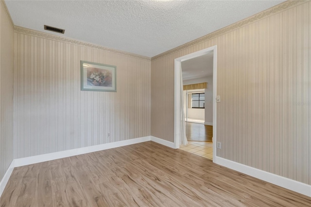 spare room with a textured ceiling and light wood-type flooring