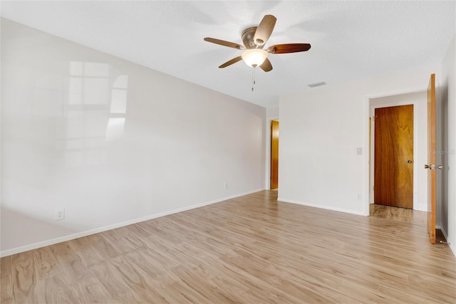 empty room with ceiling fan, a textured ceiling, and light wood-type flooring