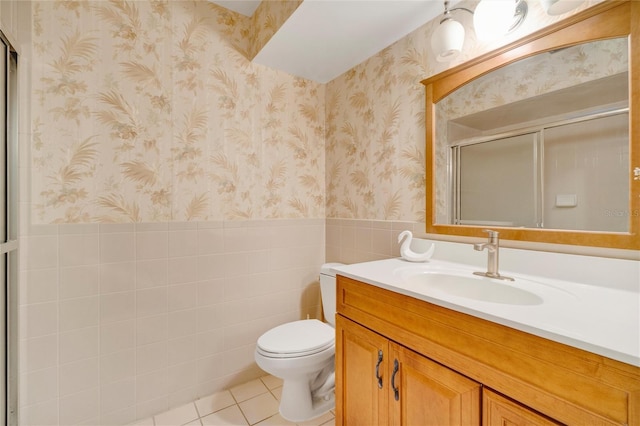 bathroom with a shower with door, vanity, toilet, and tile patterned floors