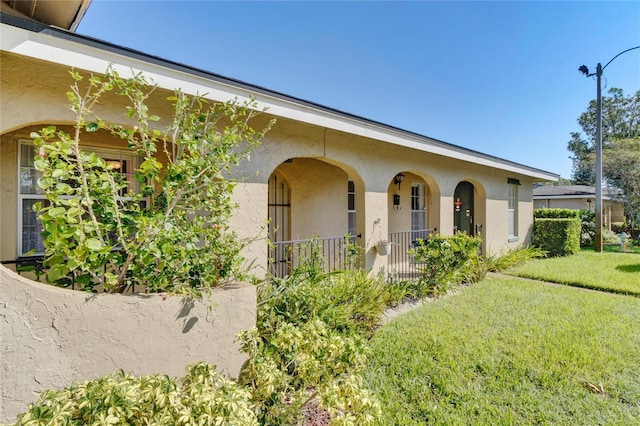 view of front of house featuring stucco siding and a front lawn