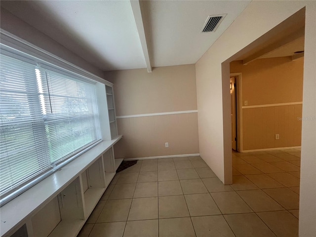 interior space featuring beam ceiling, wood walls, and light tile patterned floors