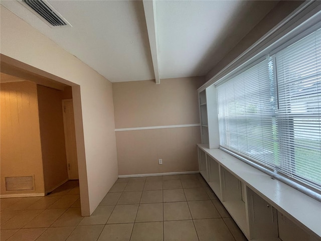 spare room featuring beam ceiling and light tile patterned flooring