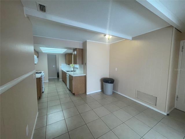 kitchen with beamed ceiling, white range oven, light tile patterned floors, and sink