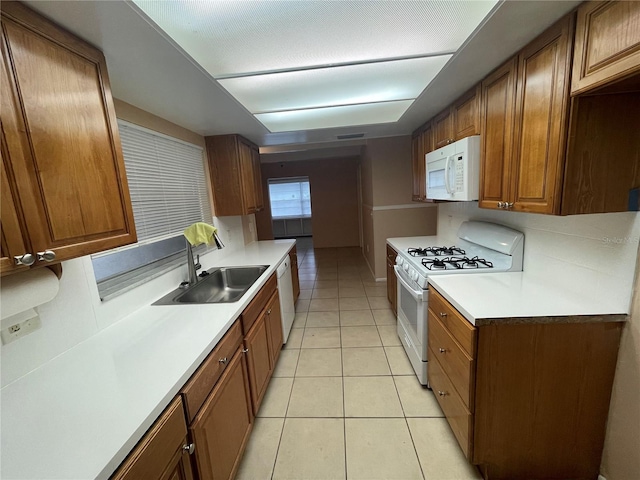 kitchen with white appliances, light tile patterned floors, and sink