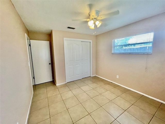 unfurnished bedroom with ceiling fan, a closet, and light tile patterned floors