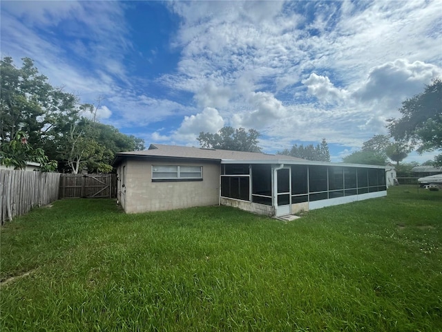 back of property with a yard and a sunroom