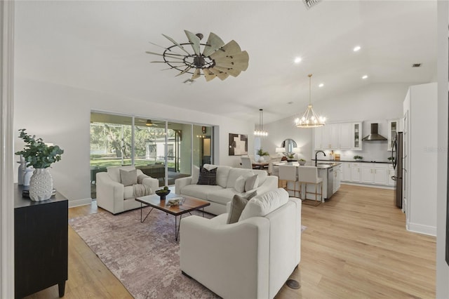 living room featuring ceiling fan, lofted ceiling, sink, and light hardwood / wood-style flooring