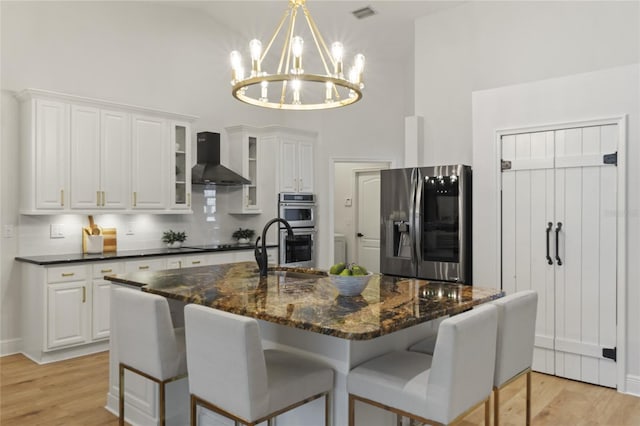 kitchen featuring appliances with stainless steel finishes, wall chimney exhaust hood, a chandelier, and white cabinetry