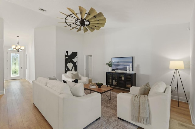 living room with ceiling fan with notable chandelier and light hardwood / wood-style floors