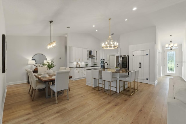 dining area with light hardwood / wood-style floors and high vaulted ceiling