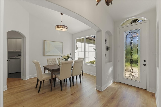 dining area featuring lofted ceiling, washer / dryer, and light wood-type flooring