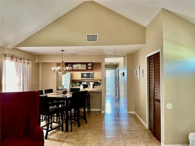 dining space featuring high vaulted ceiling, light tile patterned flooring, and a chandelier