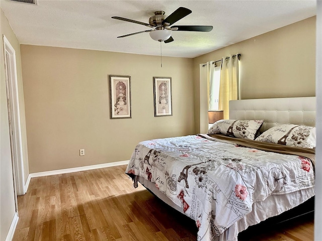 bedroom with hardwood / wood-style floors, a textured ceiling, and ceiling fan