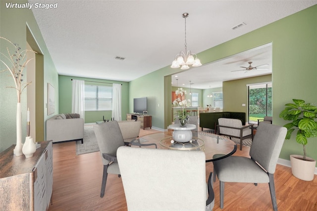 dining room with light hardwood / wood-style flooring and ceiling fan with notable chandelier