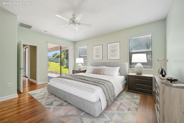 bedroom featuring ceiling fan, access to exterior, wood-type flooring, and a textured ceiling