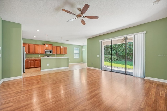 unfurnished living room with a textured ceiling and light hardwood / wood-style floors