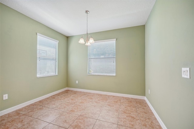 unfurnished room with a notable chandelier and light tile patterned floors