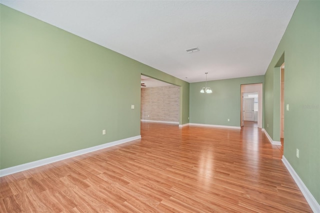 empty room featuring light hardwood / wood-style flooring and an inviting chandelier