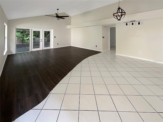 unfurnished living room featuring ceiling fan with notable chandelier, light hardwood / wood-style floors, and vaulted ceiling