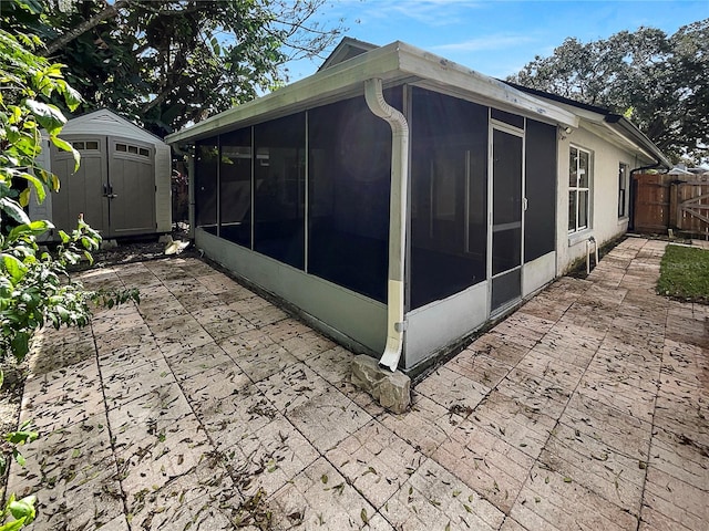 view of home's exterior with a storage shed, a sunroom, and a patio area