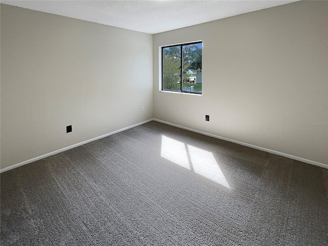 unfurnished room with dark carpet and a textured ceiling