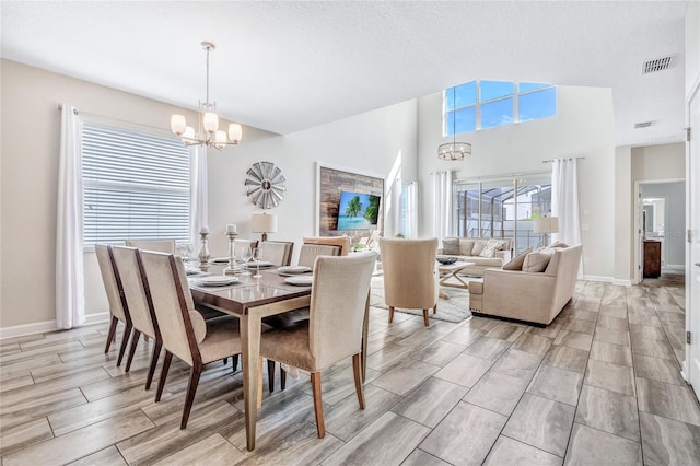 dining space with an inviting chandelier, vaulted ceiling, a textured ceiling, and light hardwood / wood-style floors