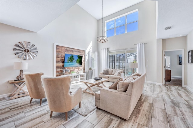 living room featuring a notable chandelier, light wood-type flooring, and a towering ceiling