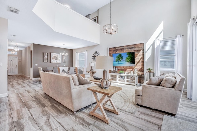 living room with an inviting chandelier, a wealth of natural light, and a high ceiling