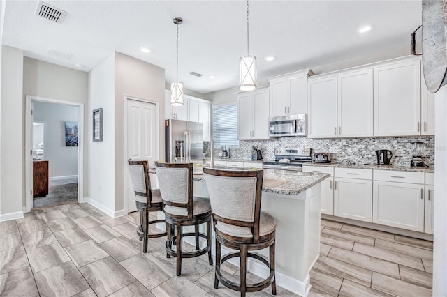 4782 Kings Castle Cir, Kissimmee, FL 34746 - kitchen with appliances with stainless steel finishes, backsplash, a center island, a kitchen breakfast bar, and white cabinetry