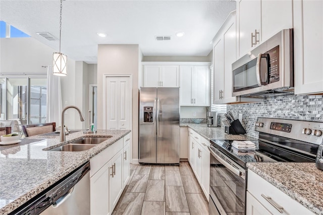 kitchen with white cabinets, appliances with stainless steel finishes, hanging light fixtures, and sink