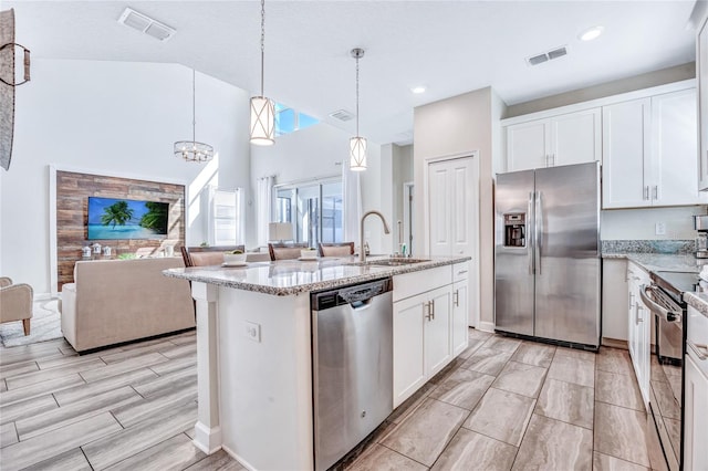 kitchen with sink, decorative light fixtures, a center island with sink, white cabinetry, and appliances with stainless steel finishes