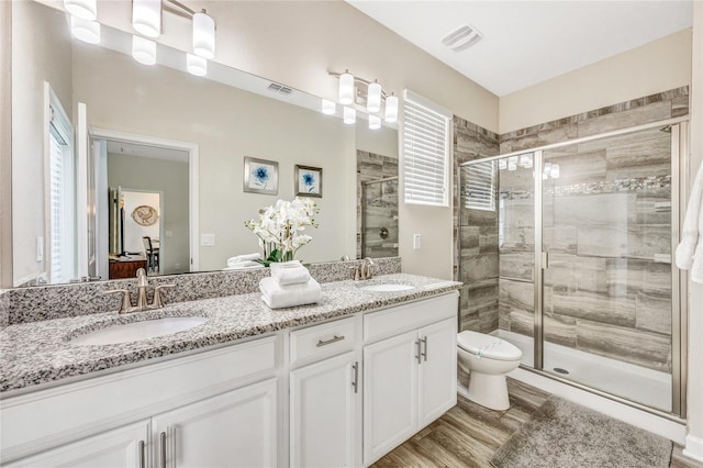 bathroom with vanity, an enclosed shower, plenty of natural light, hardwood / wood-style flooring, and toilet