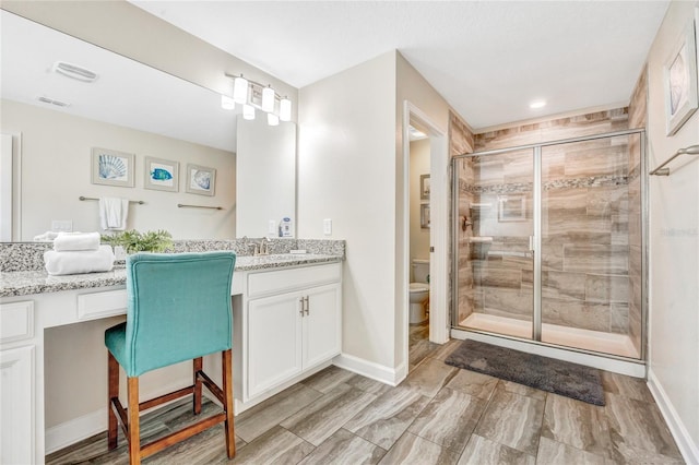 bathroom featuring vanity, toilet, and a shower with door