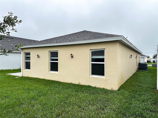 view of side of property with central air condition unit and a yard